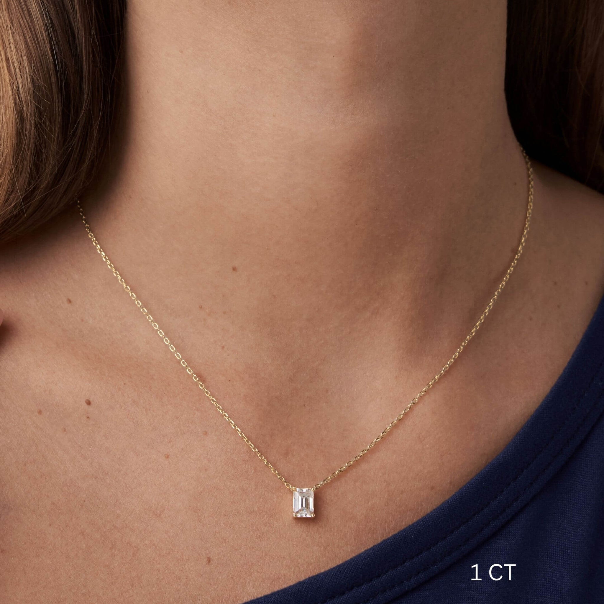 Emerald-cut moissanite pendant necklace worn at the neckline.