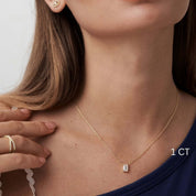 Emerald-cut moissanite pendant necklace worn at the neckline.