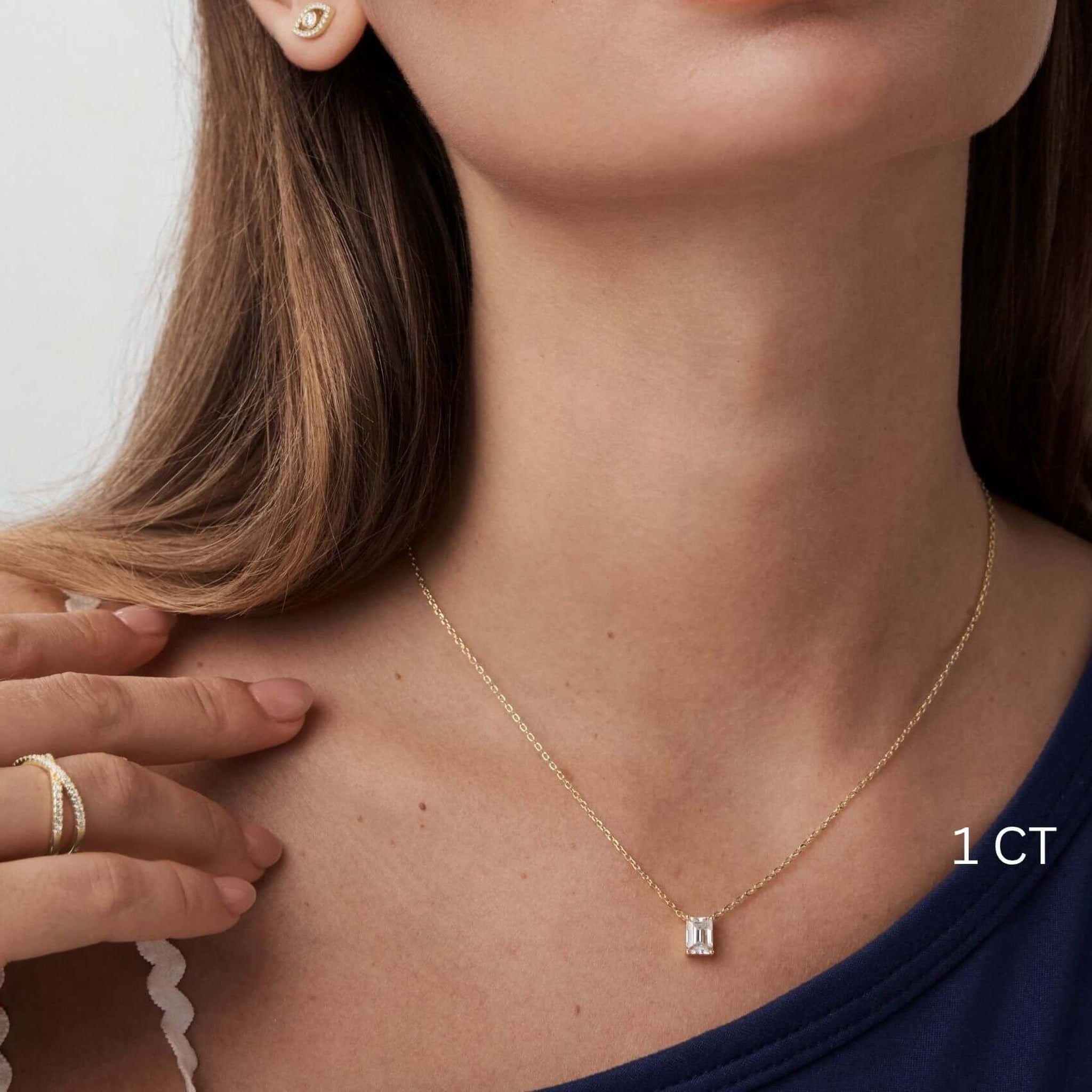 Emerald-cut moissanite pendant necklace worn at the neckline.