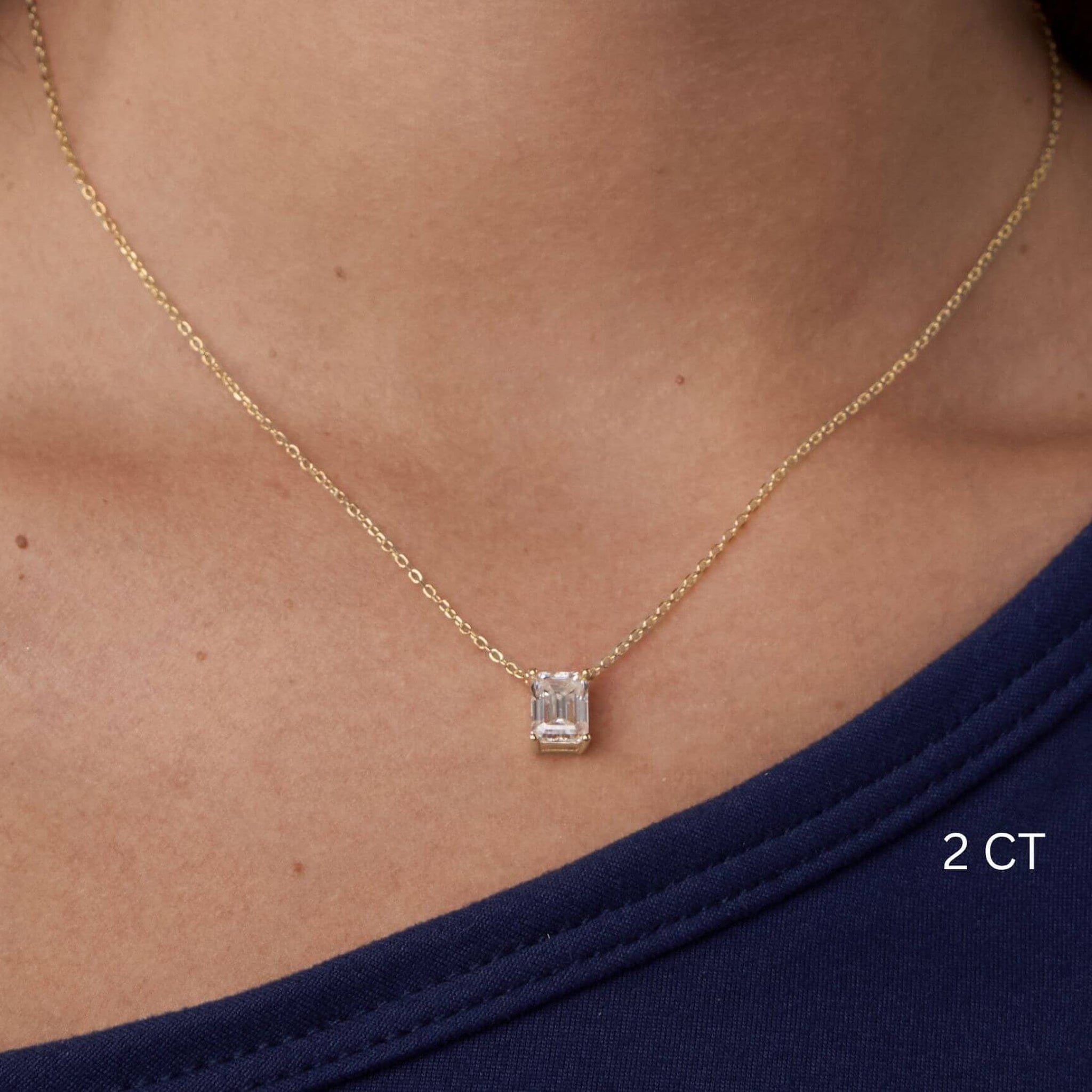 Emerald-cut moissanite pendant necklace worn at the neckline.