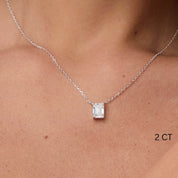 Emerald-cut moissanite pendant necklace worn at the neckline.