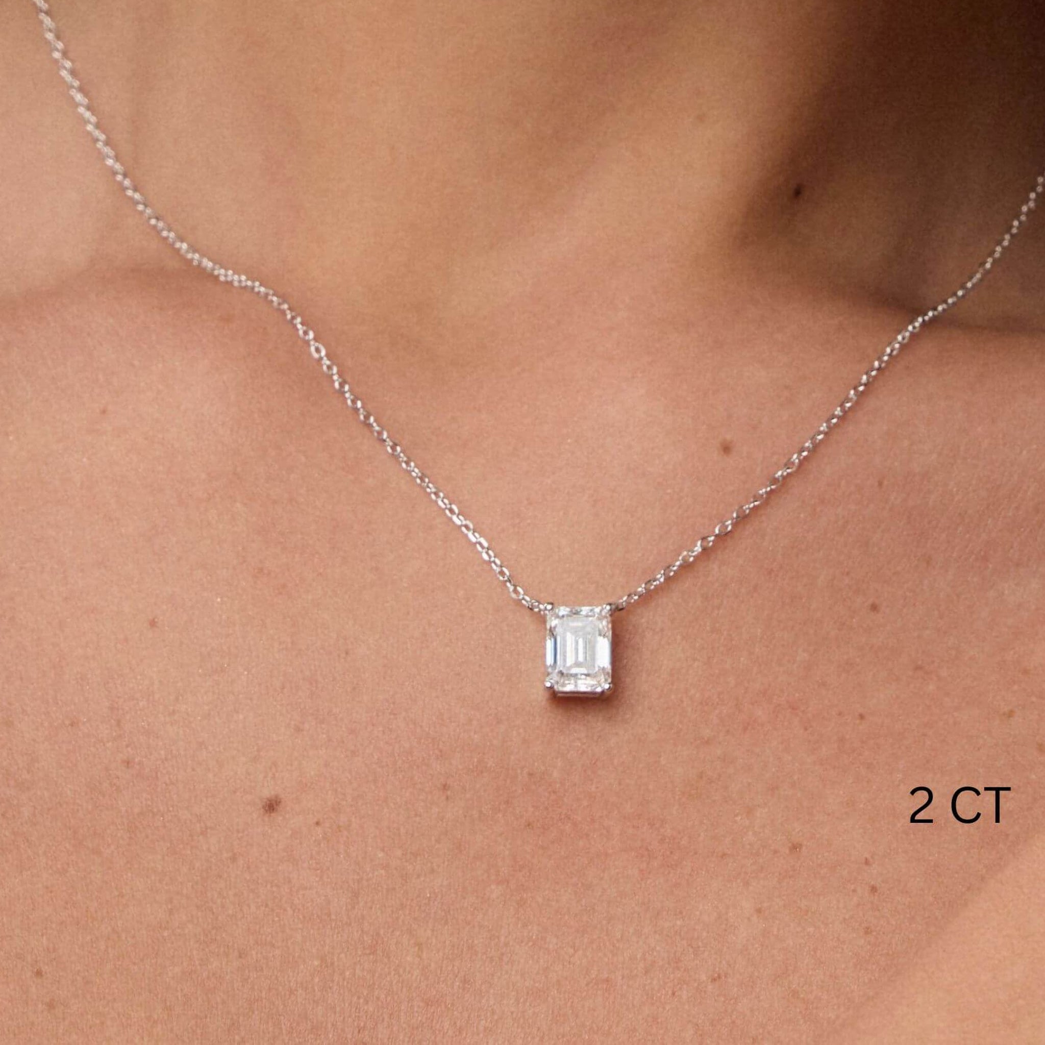 Emerald-cut moissanite pendant necklace worn at the neckline.