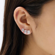 Emerald-cut moissanite stud earrings different stud sizes shown together on the ear.