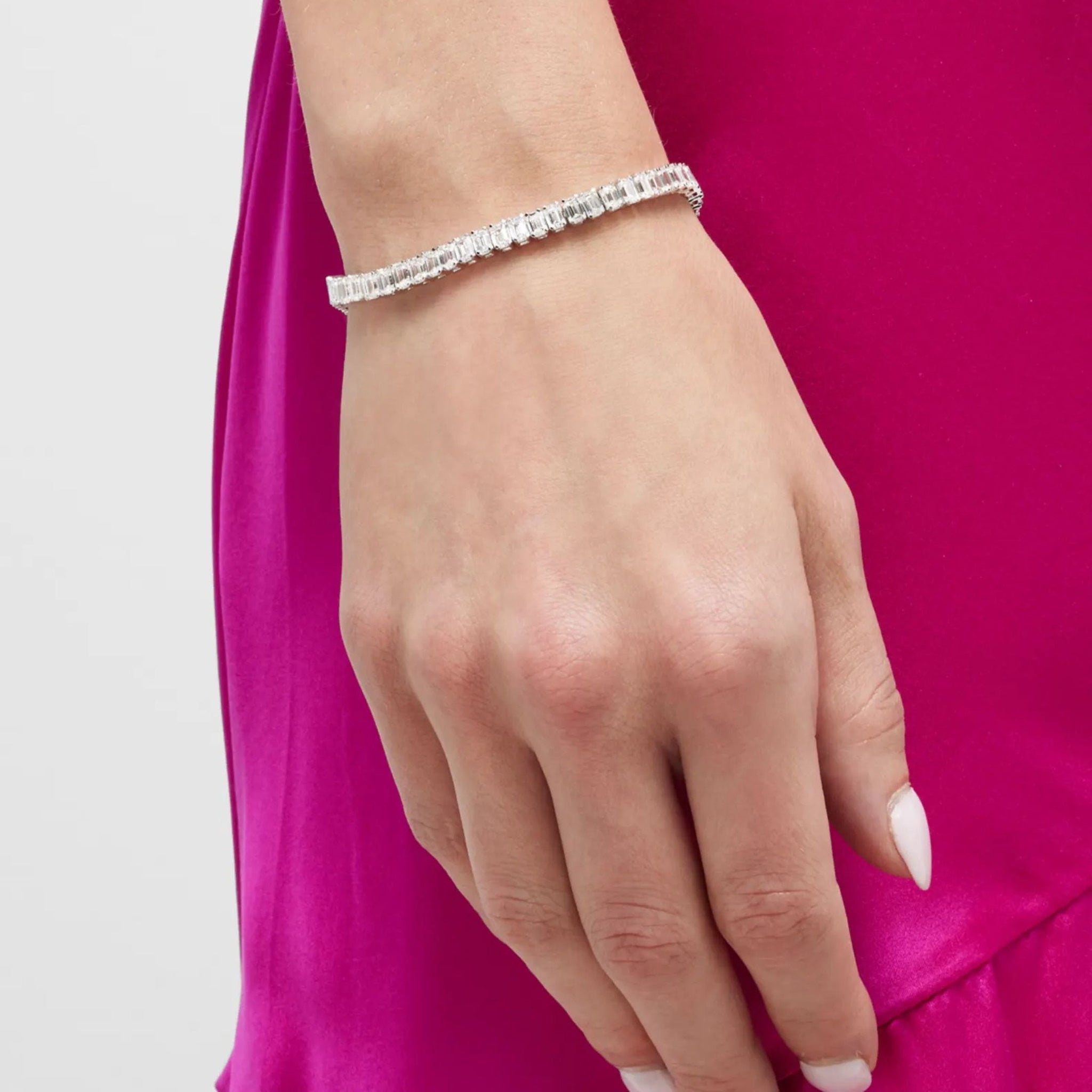 Emerald-cut moissanite tennis bracelet worn on the wrist.