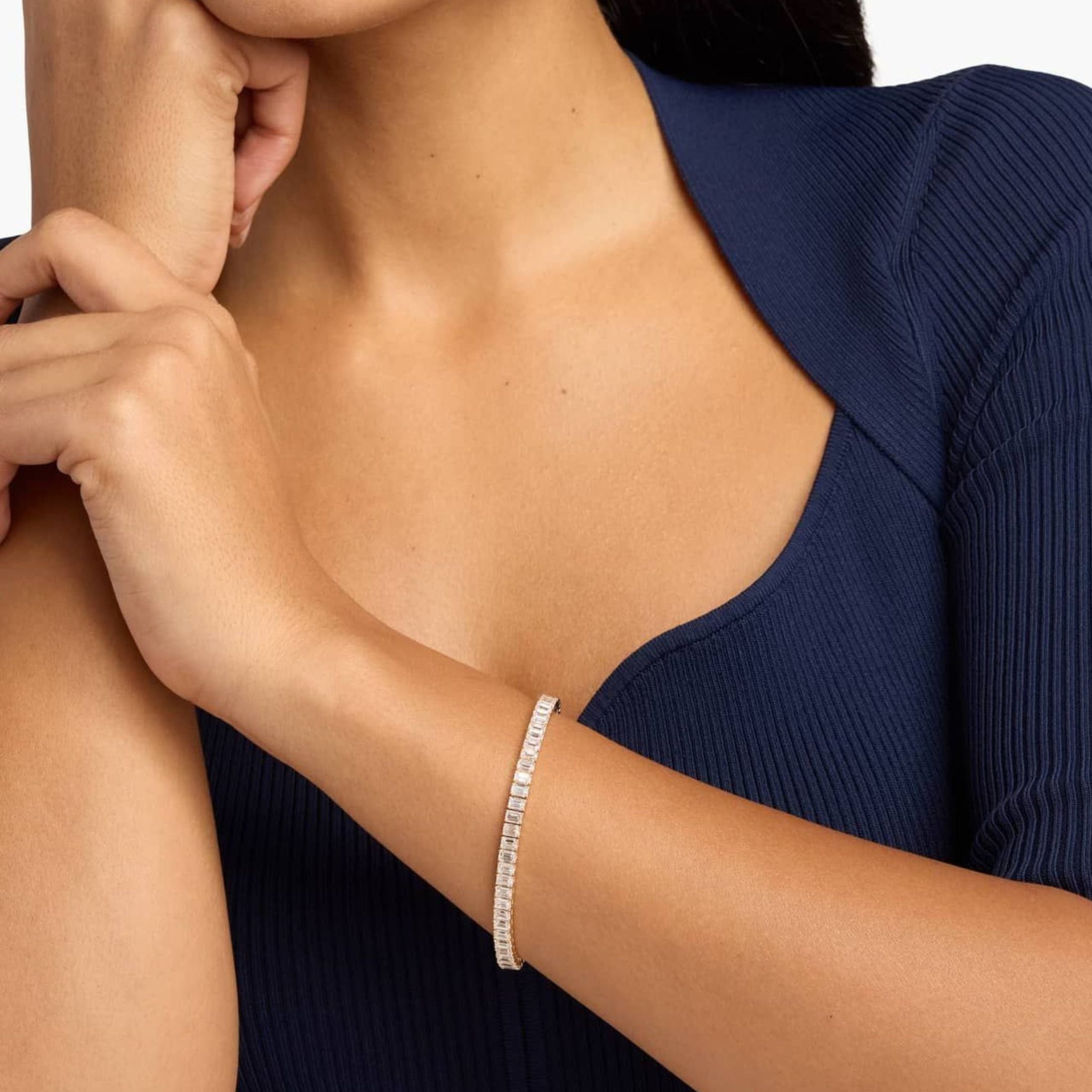 Emerald-cut moissanite tennis bracelet worn on the wrist.