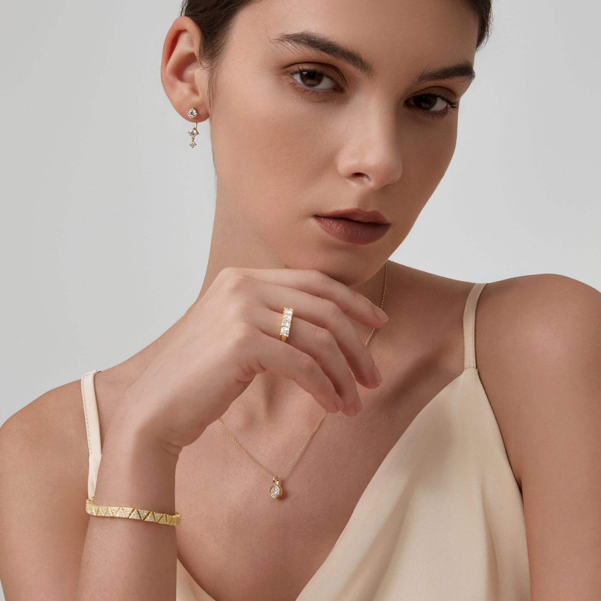 Floating three-stone moissanite drop earrings worn on the ear.