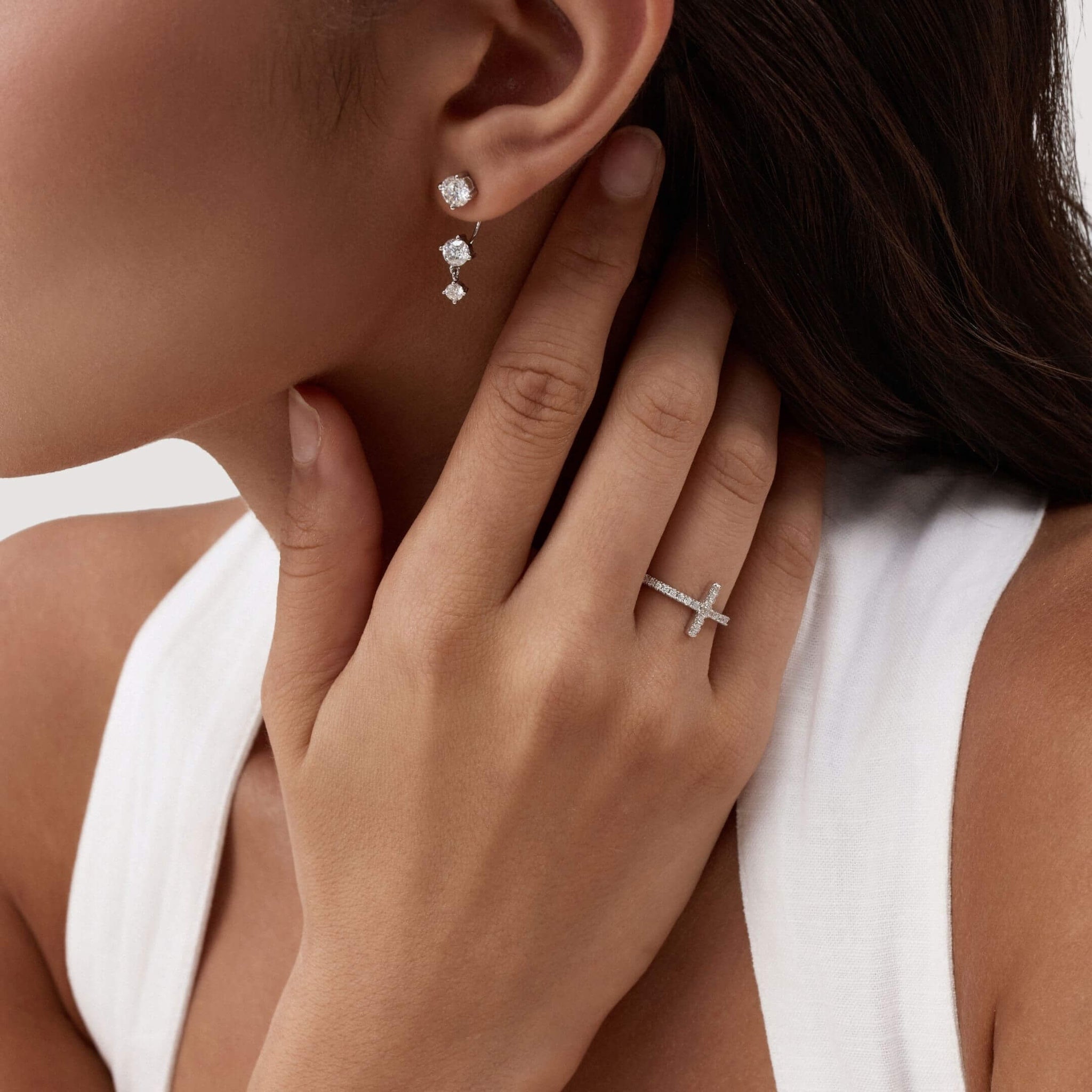 Floating three-stone moissanite drop earrings worn on the ear.