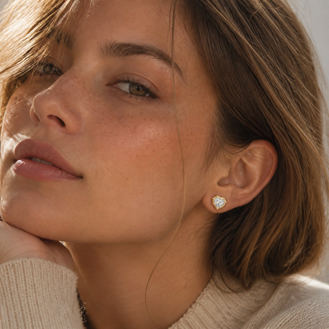Heart-cut moissanite bezel-prong stud earrings in yellow gold vermeil, worn by a model.