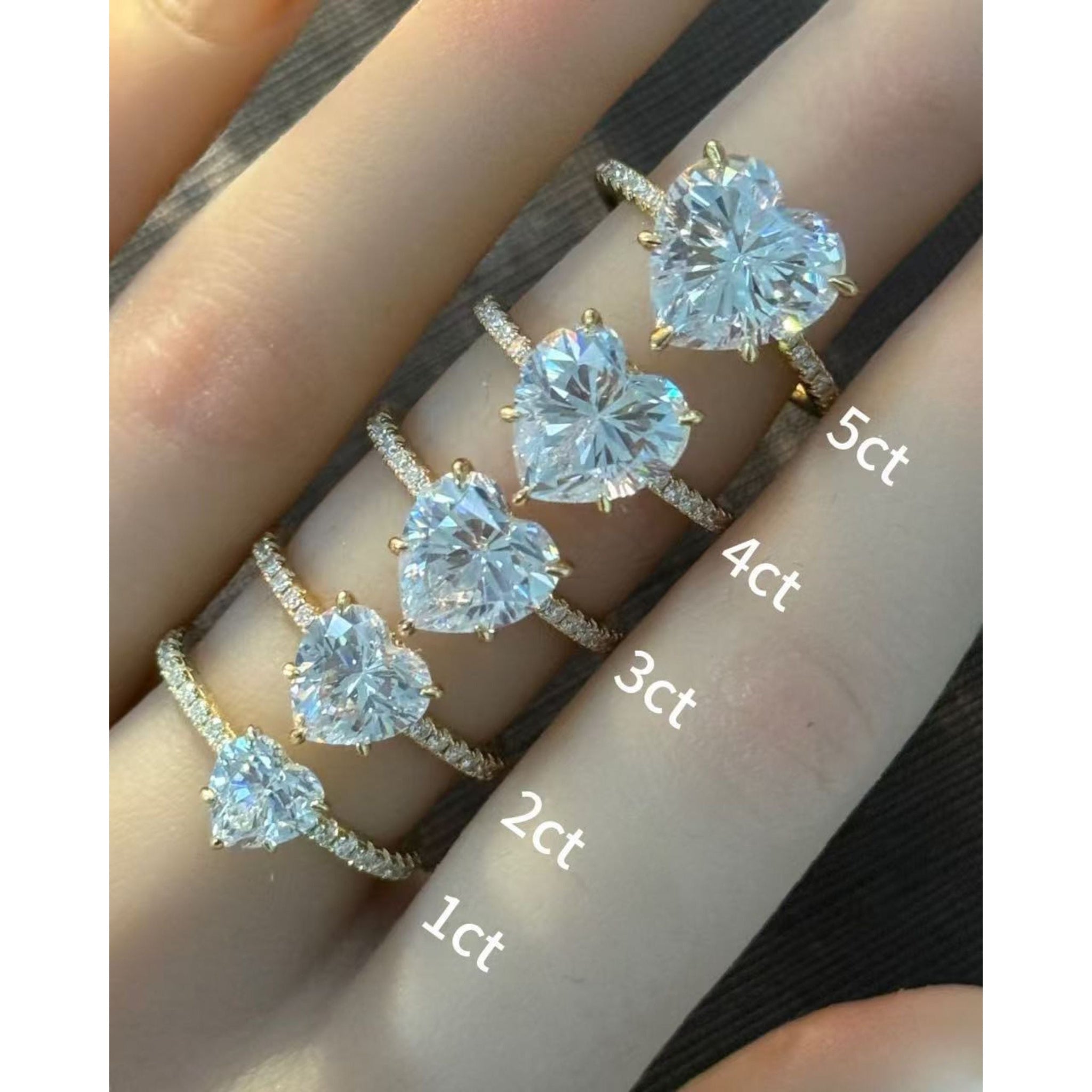 Heart-cut moissanite hidden halo ring with pavé band rings arranged across fingers for a carat-size comparison.