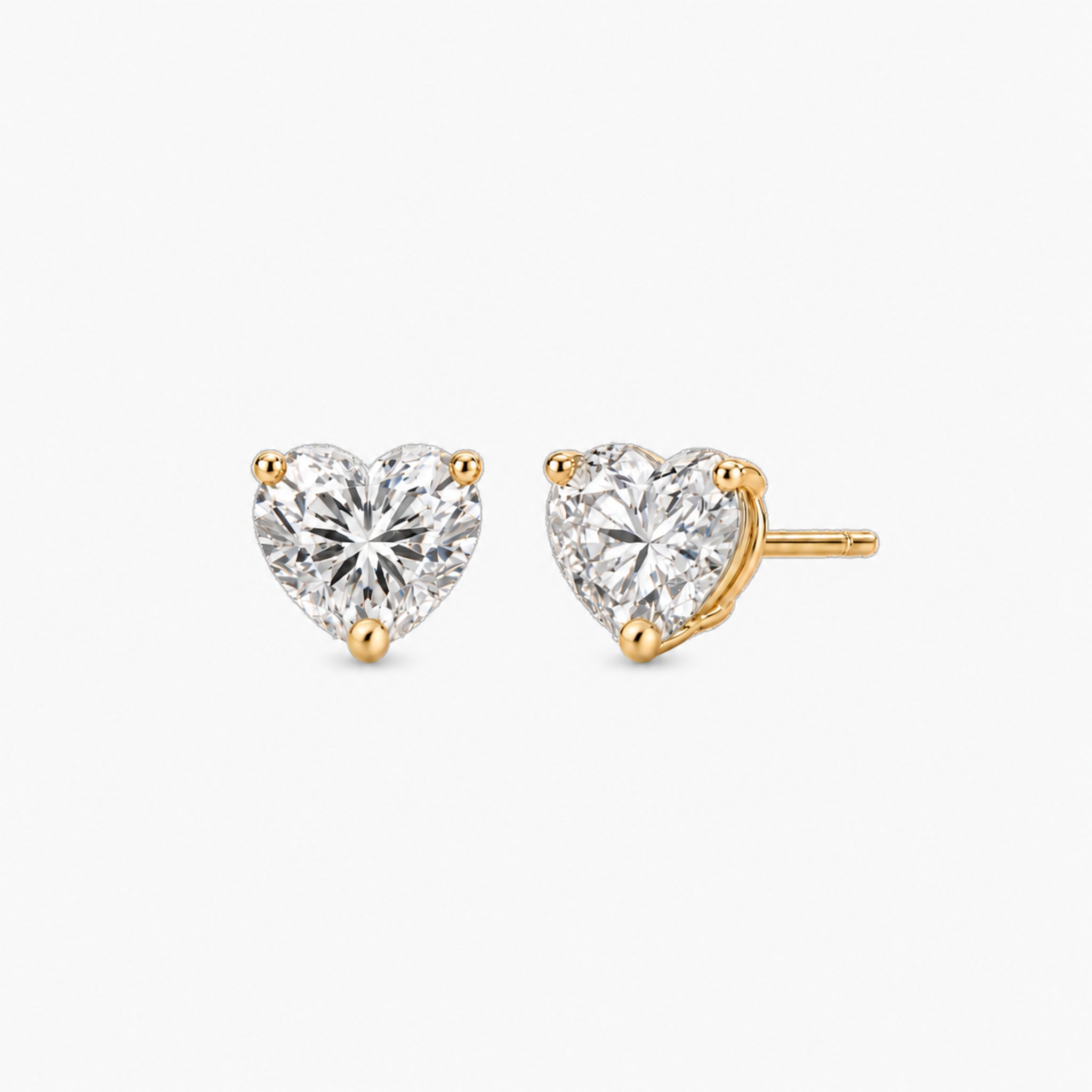 Heart-cut moissanite stud earrings in yellow gold vermeil, front and three-quarter views.