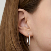 Large pavé moissanite hoop earrings worn on the ear.