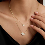 Layered pavé moissanite heart necklace worn at the neckline.