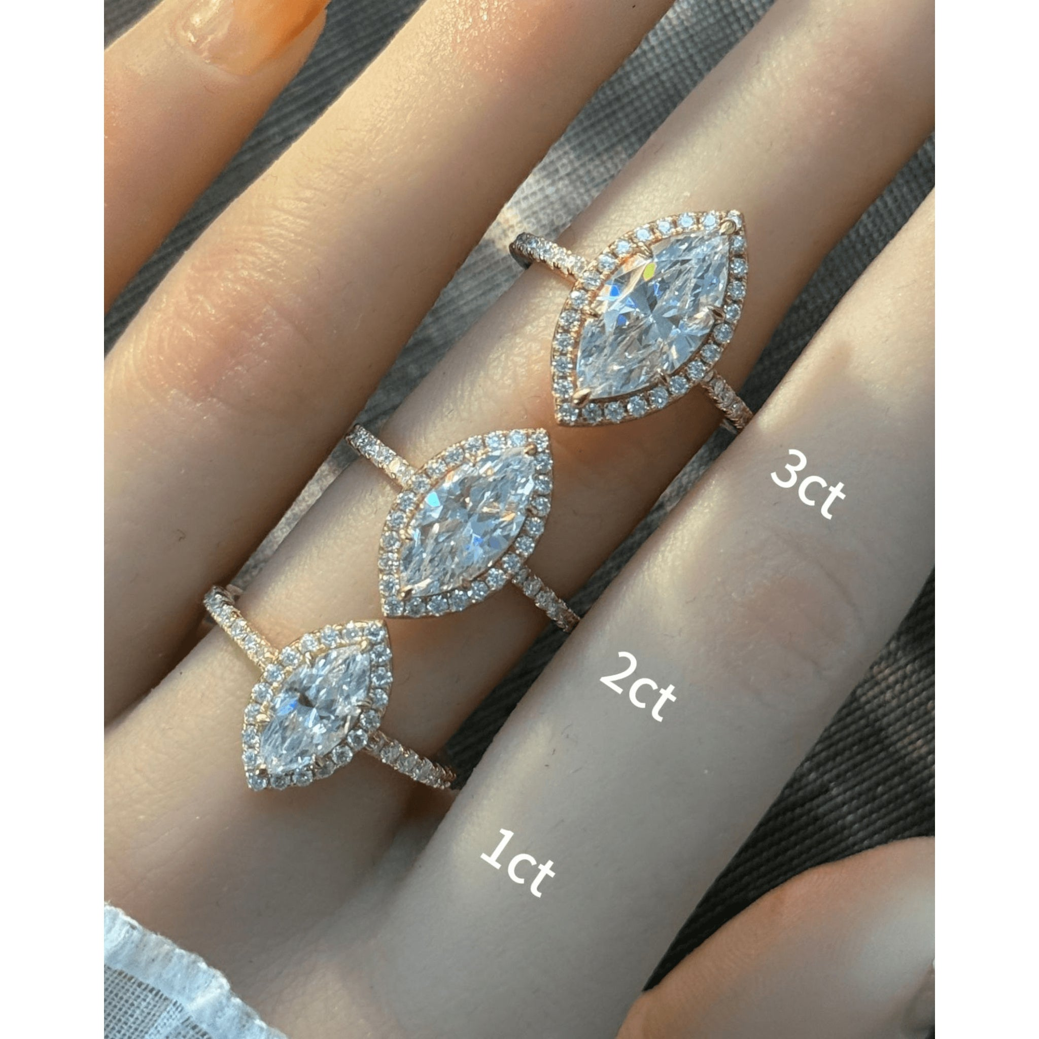 Marquise-cut moissanite halo ring with pavé band rings arranged across fingers for a carat-size comparison.