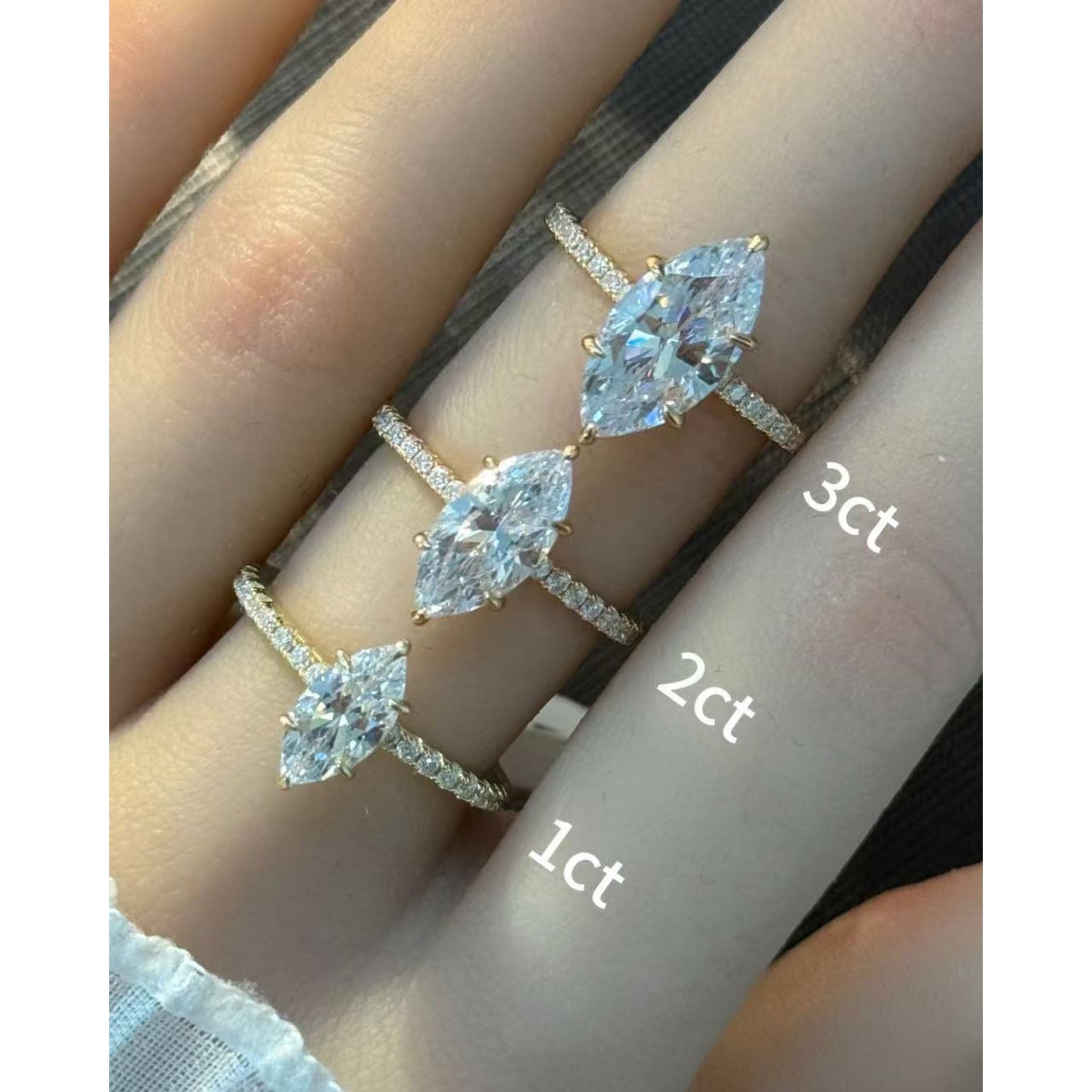Marquise-cut moissanite hidden halo ring with pavé band rings arranged across fingers for a carat-size comparison.