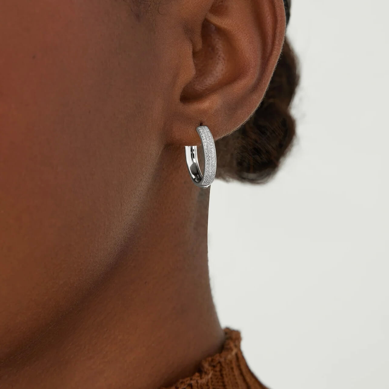 Medium bold pavé moissanite hoop earrings worn on the ear.