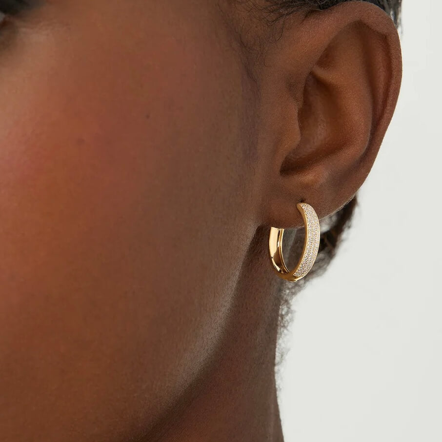Medium bold pavé moissanite hoop earrings worn on the ear.