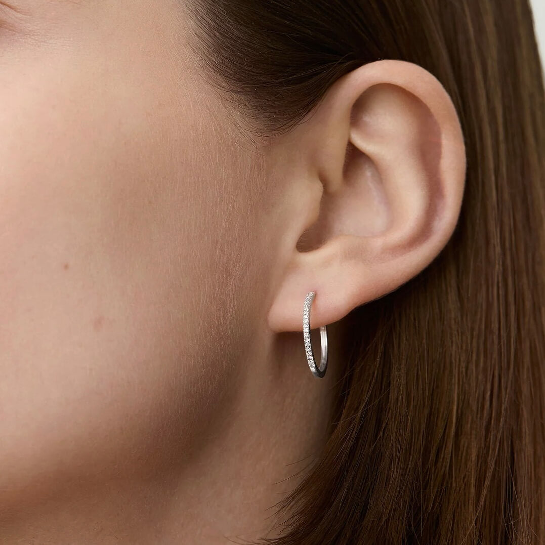 Medium pavé moissanite hoop earrings worn on the ear.