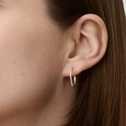 Medium pavé moissanite hoop earrings worn on the ear.