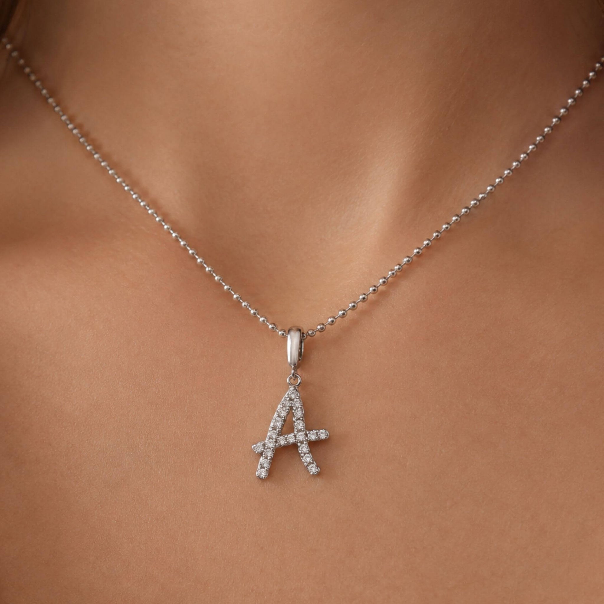 Moissanite abstract initial necklace letter A pendant worn at the neckline.