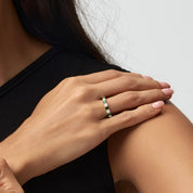 Moissanite and lab-grown emerald eternity ring worn on a finger.
