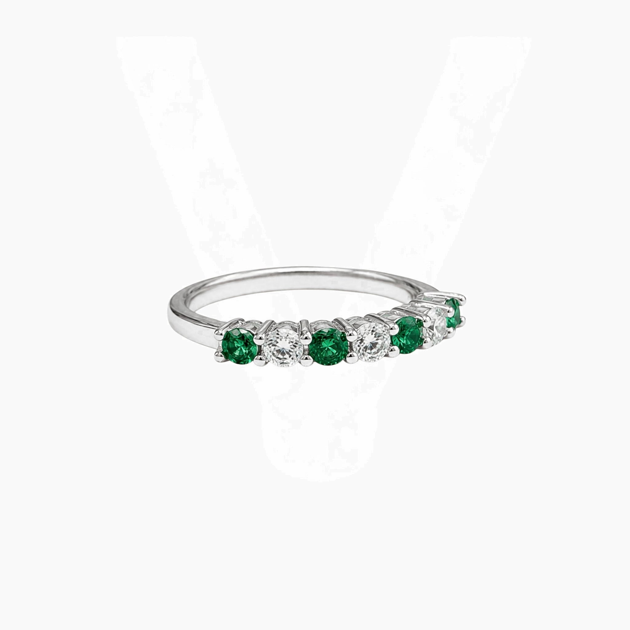 Moissanite and lab-grown emerald half eternity ring in white gold vermeil, angled view.