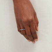 Moissanite and lab-grown sapphire eternity ring worn on a finger.