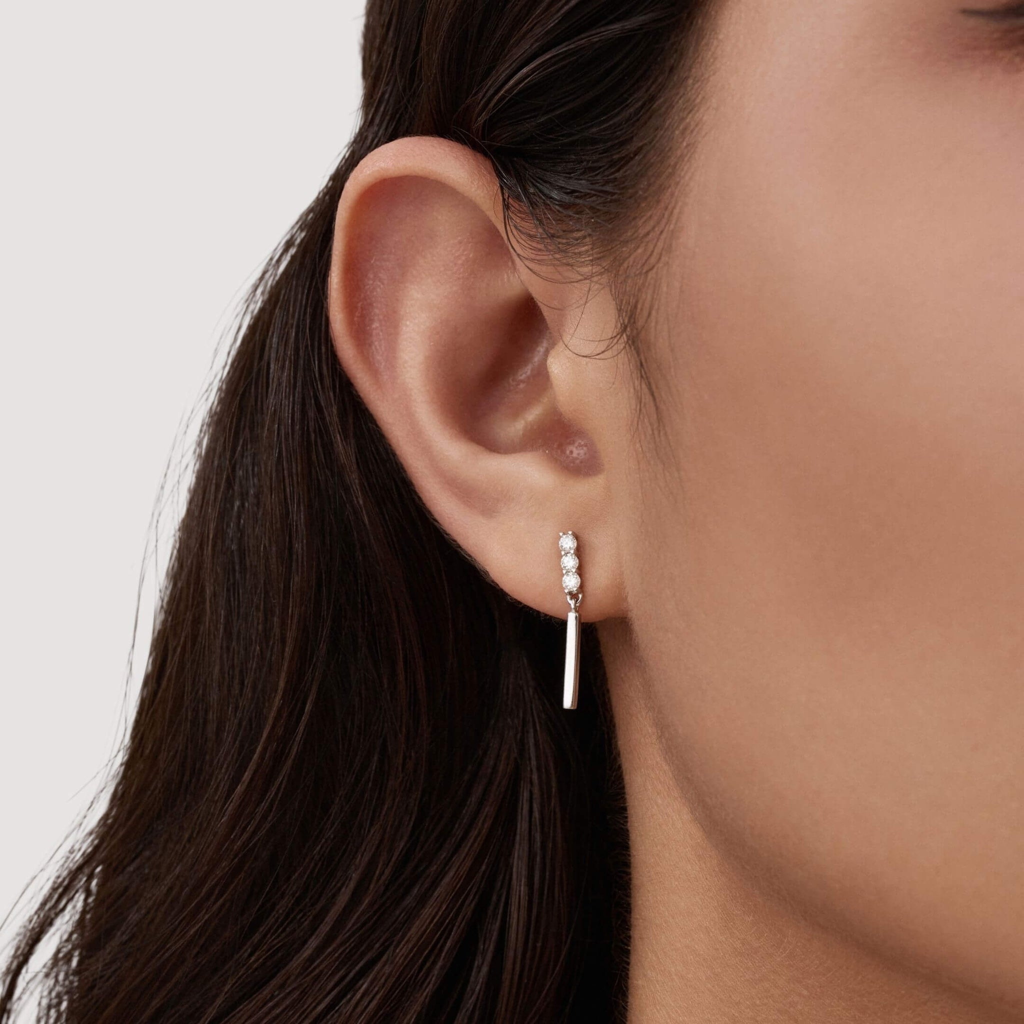 Moissanite bar drop earrings worn on the ear.