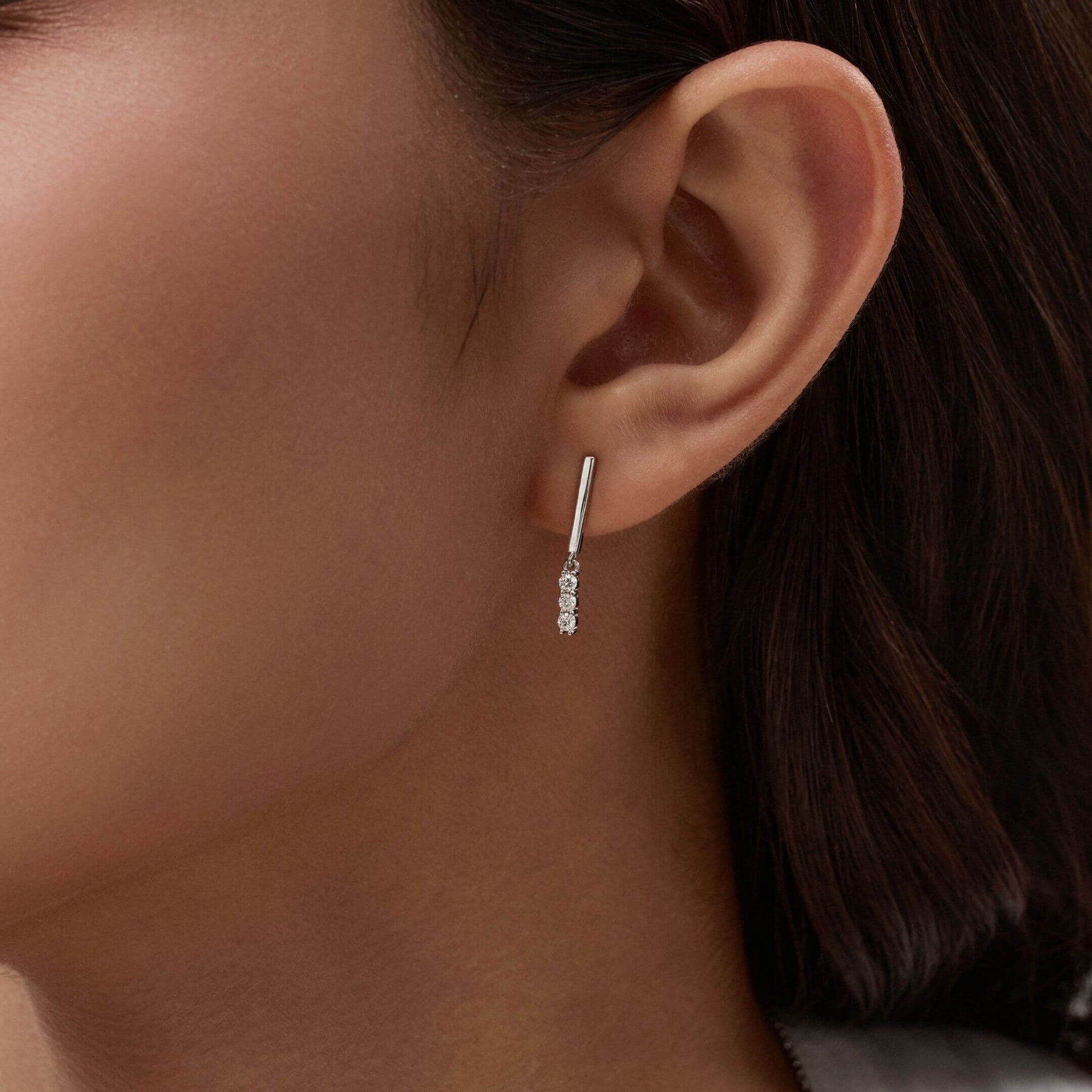 Moissanite bar drop earrings worn on the ear.