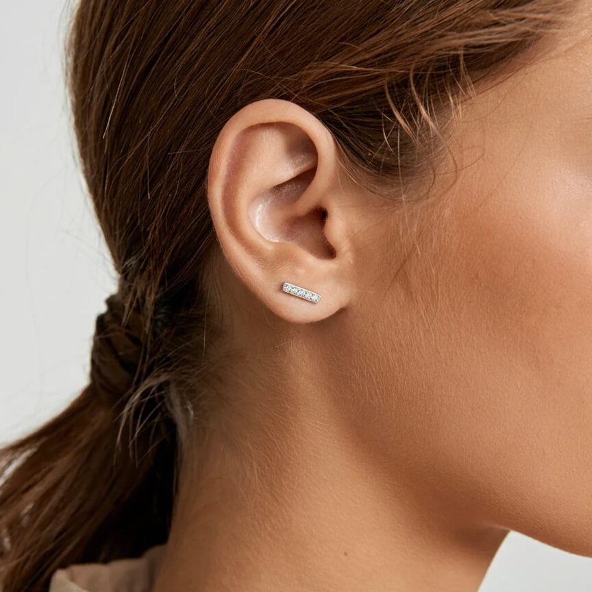 Moissanite bar stud earrings worn on the ear.