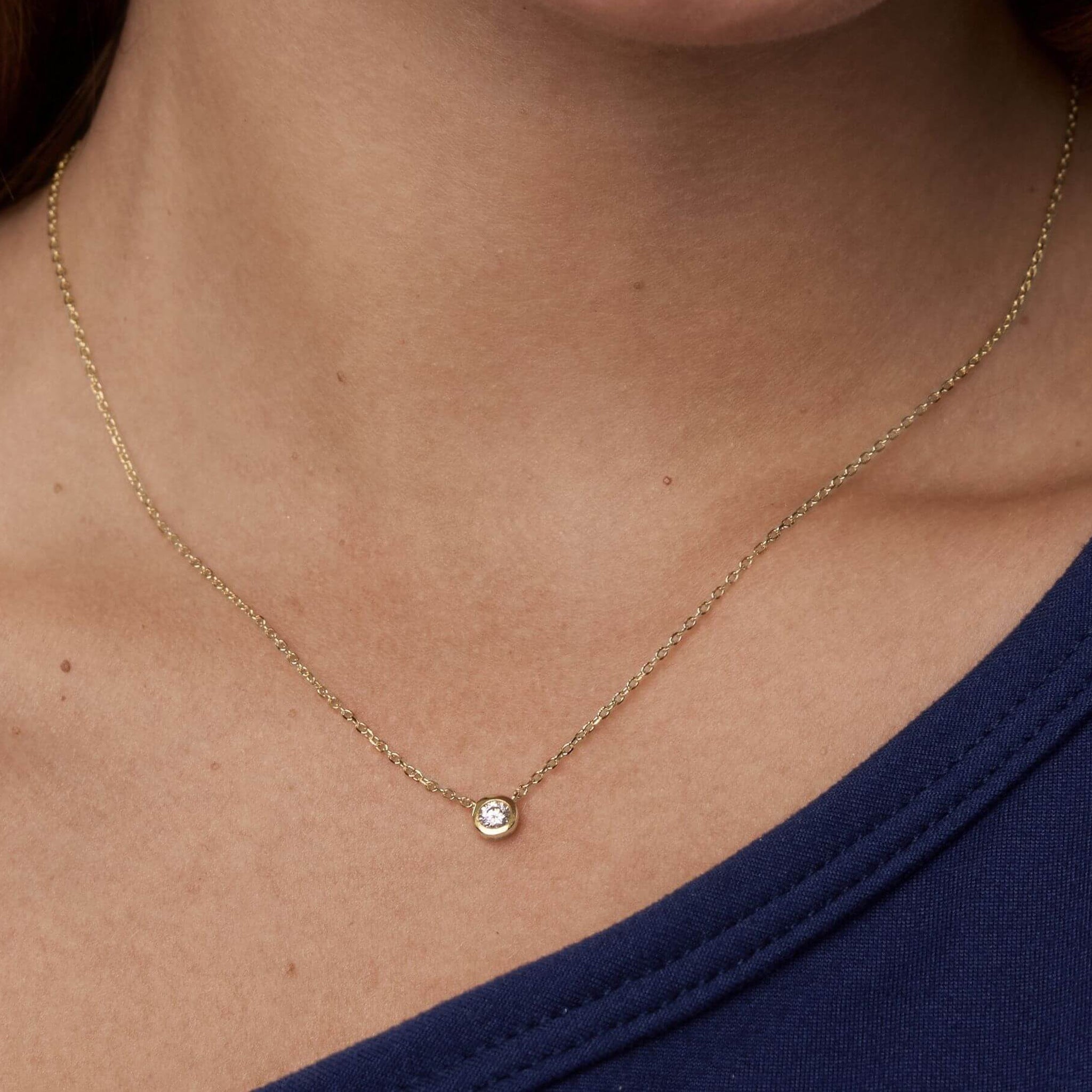 Moissanite bezel pendant necklace worn at the neckline.