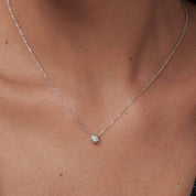 Moissanite bezel pendant necklace worn at the neckline.