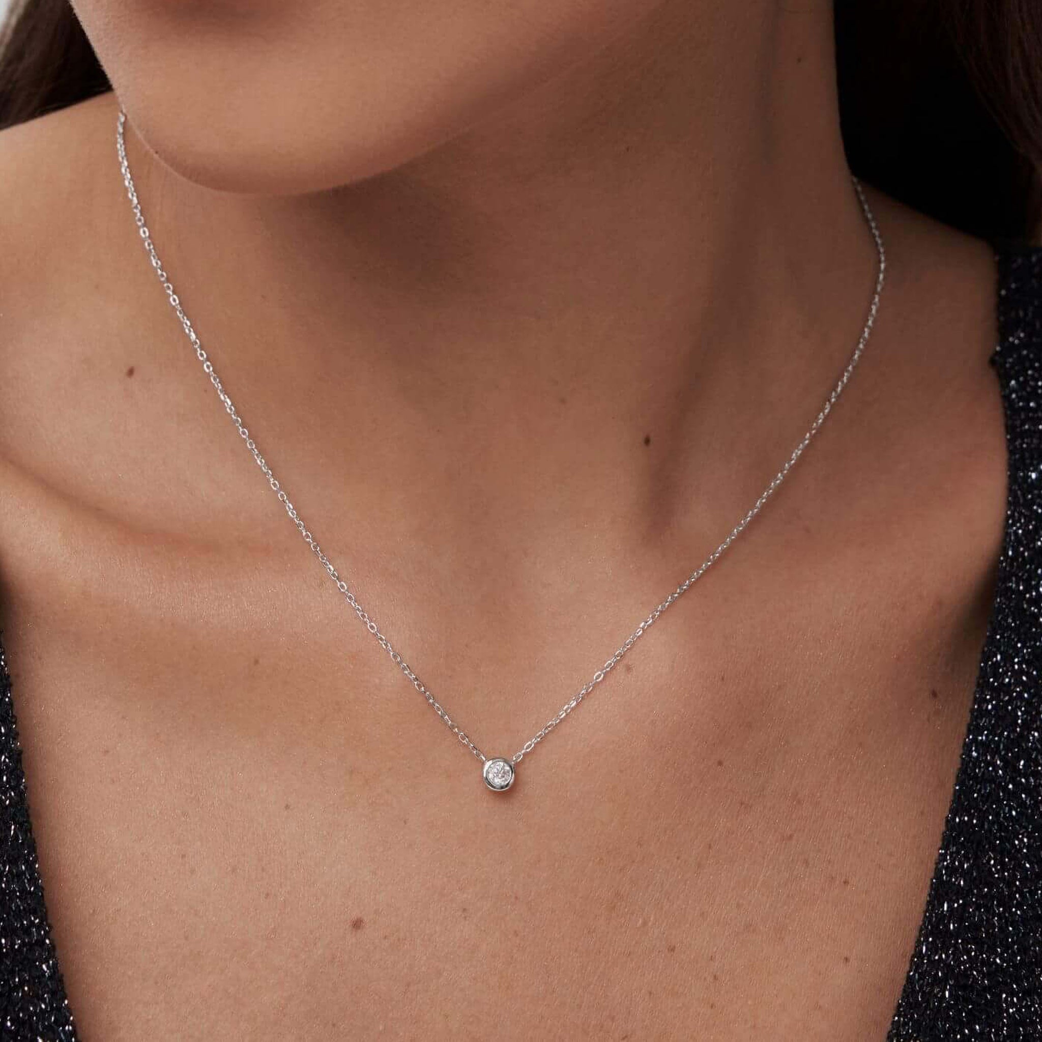 Moissanite bezel pendant necklace worn at the neckline.