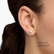 Moissanite bezel stud earrings worn on the ear, 1 ct per pair with 0.5 ct per stone.