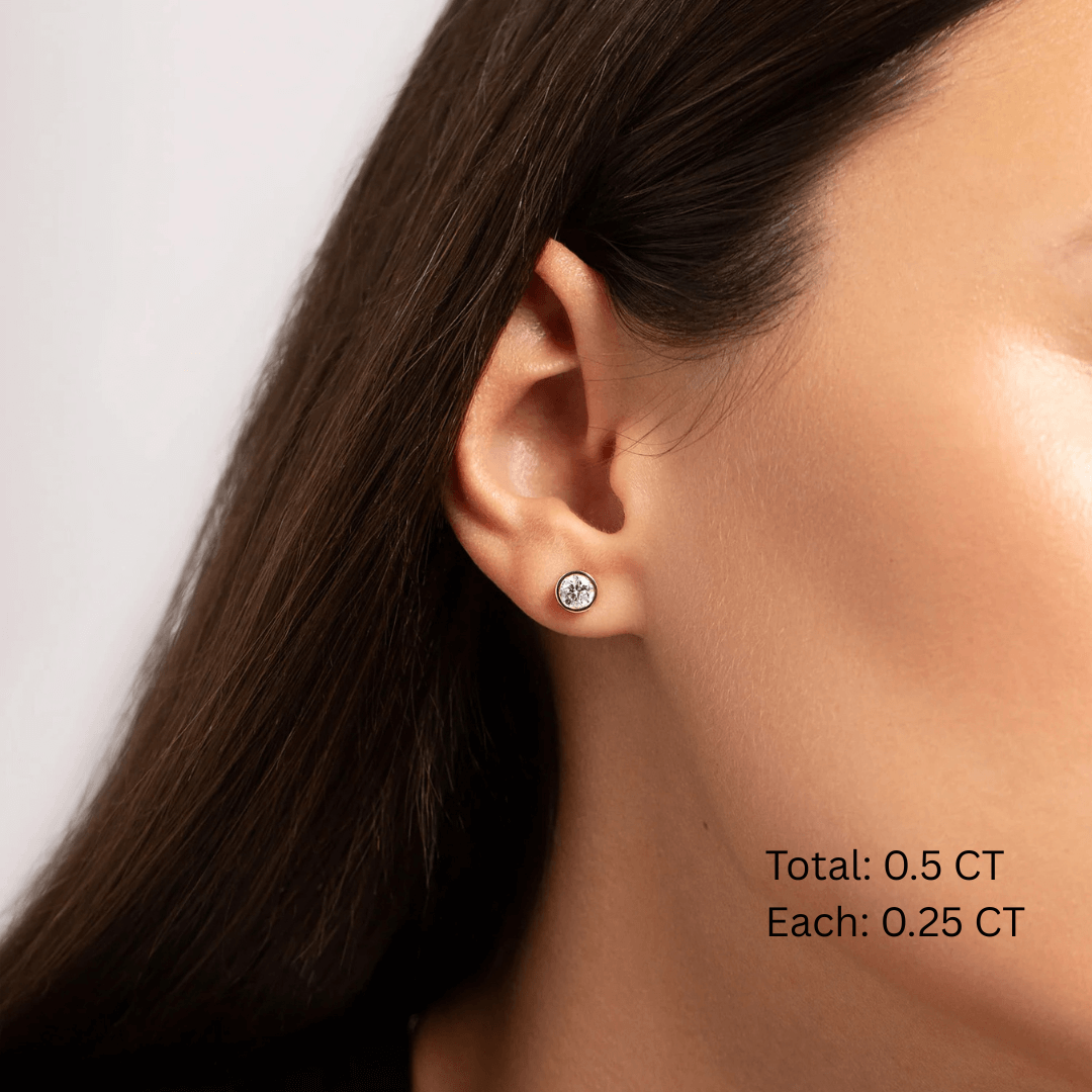 Moissanite bezel stud earrings worn on the ear, 0.5 ct per pair with 0.25 ct per stone.