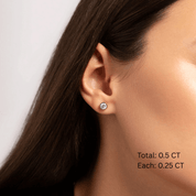 Moissanite bezel stud earrings worn on the ear, 0.5 ct per pair with 0.25 ct per stone.