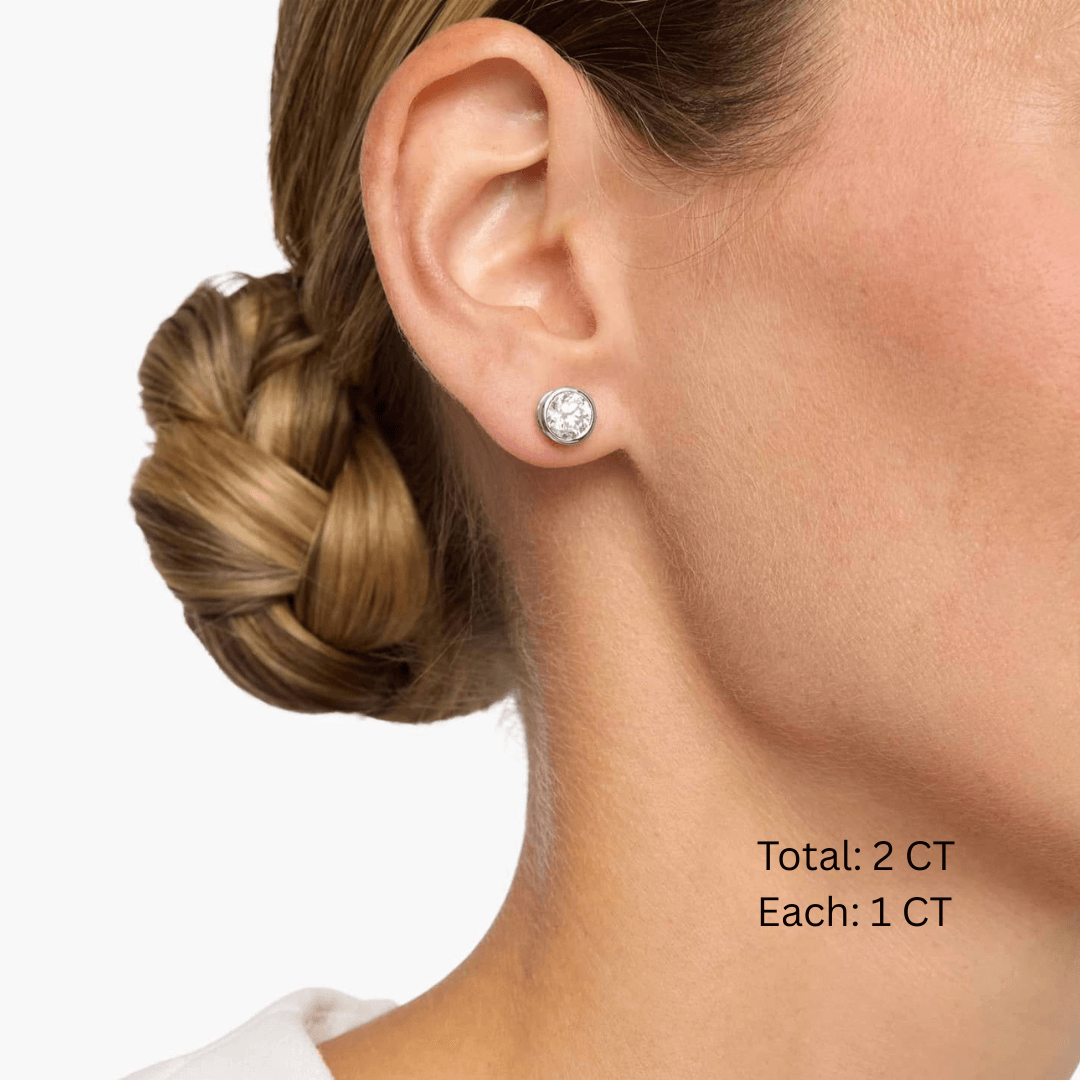 Moissanite bezel stud earrings worn on the ear, 2 ct per pair with 1 ct per stone.