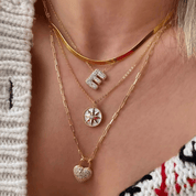 Moissanite bubble initial necklace initial pendant layered with other necklaces.