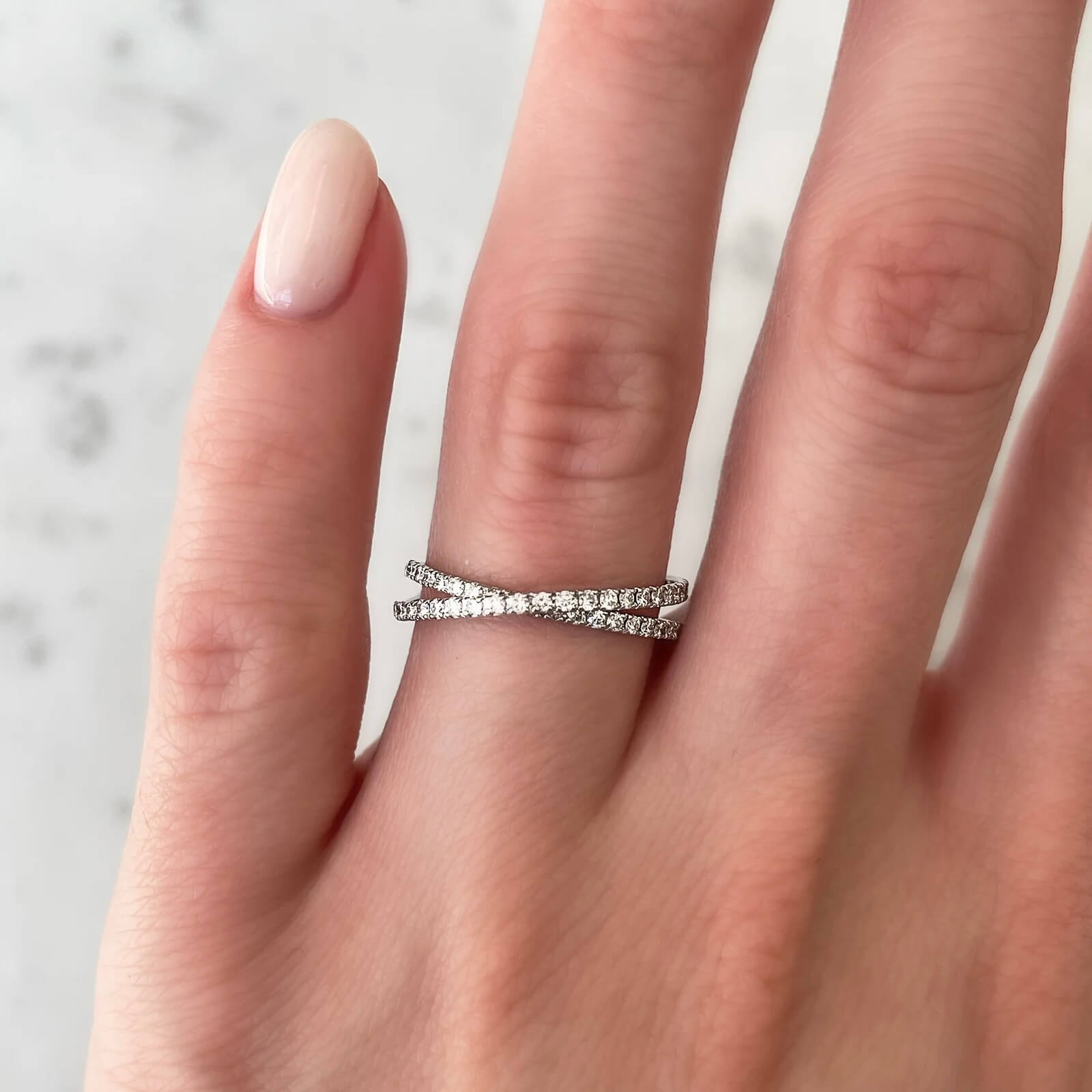 Moissanite crisscross ring worn on a finger.