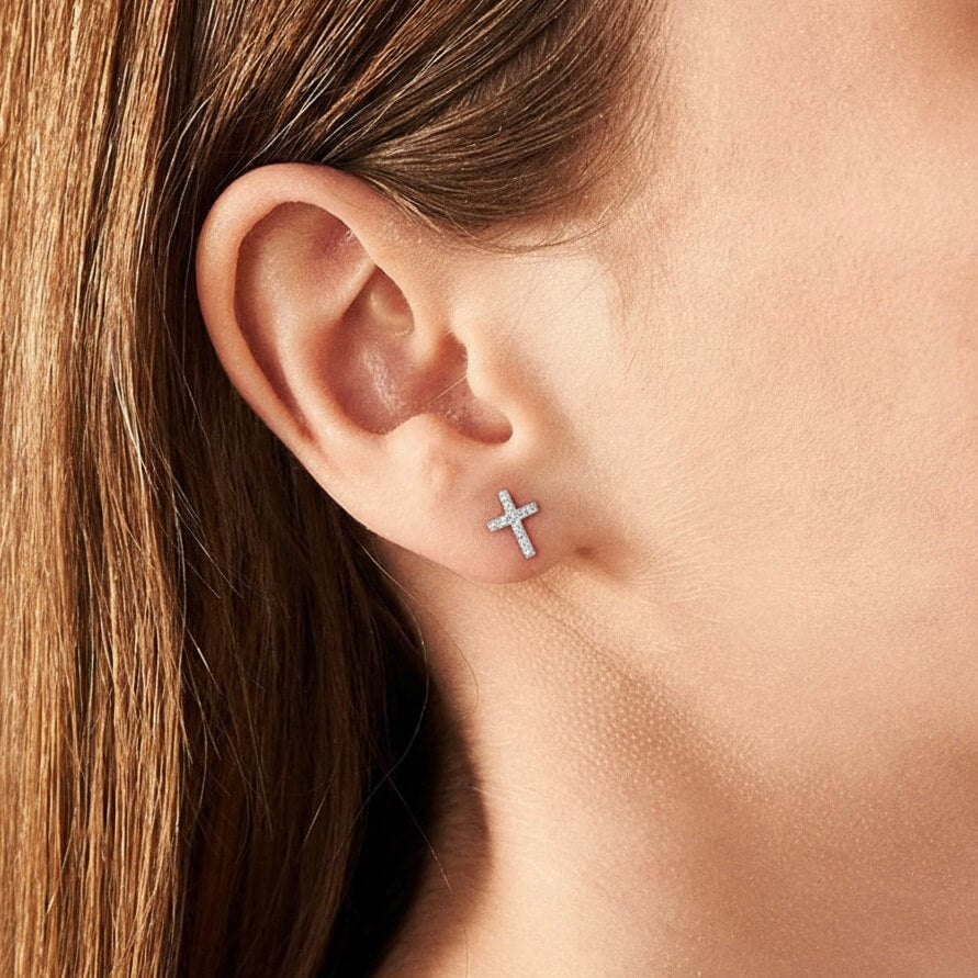 Moissanite cross stud earrings worn on the ear.