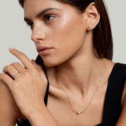 Moissanite curved bar solitaire necklace worn at the neckline.