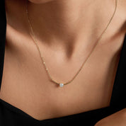 Moissanite curved bar solitaire necklace worn at the neckline.