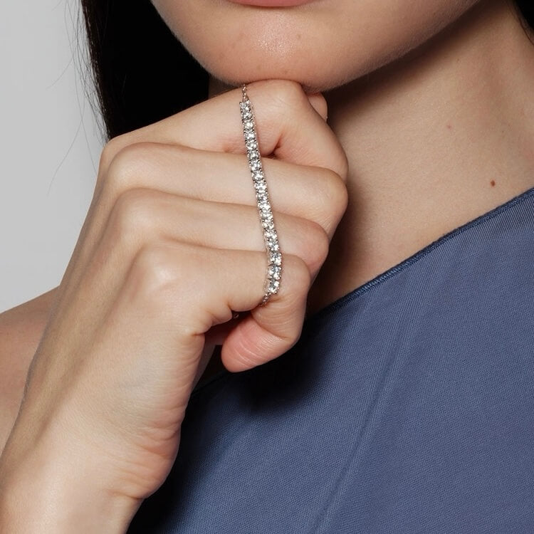 Moissanite half tennis bolo bracelet held beside the face.