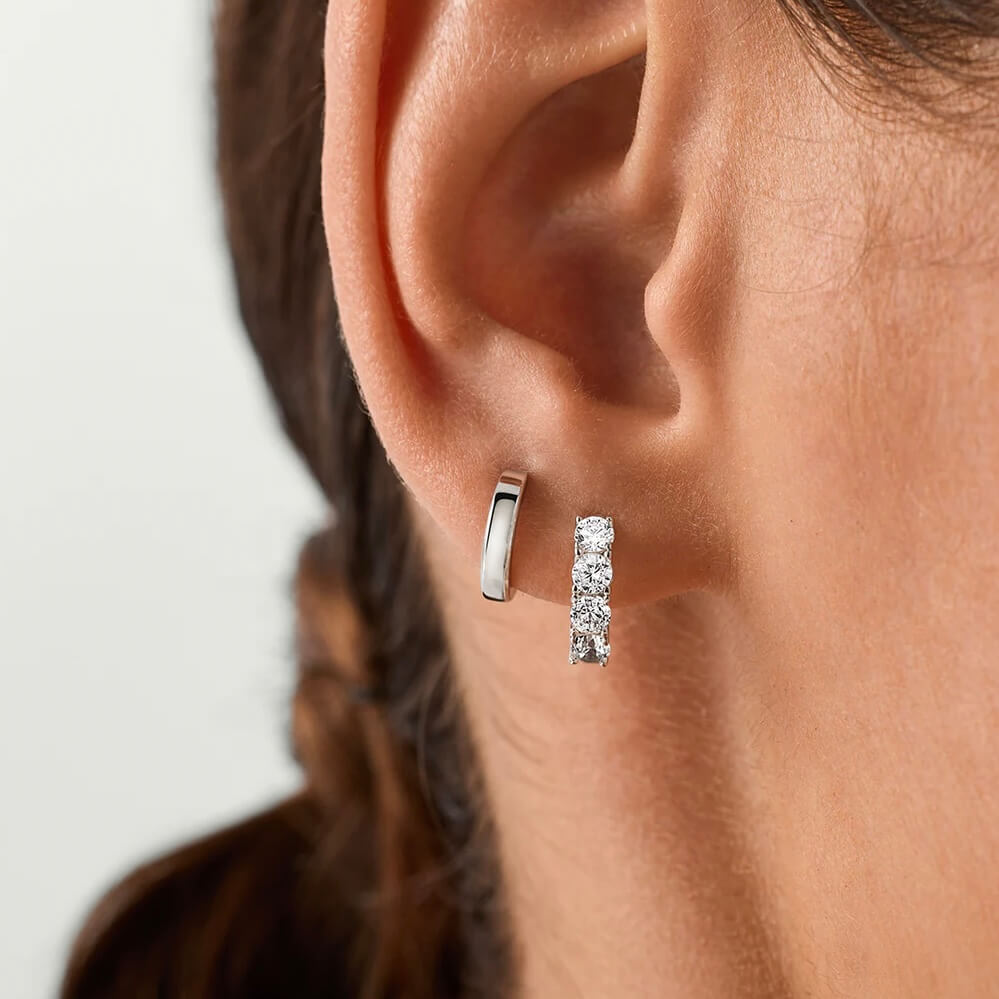 Moissanite huggie hoop earrings worn on the ear.