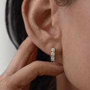 Moissanite huggie hoop earrings worn on the ear.