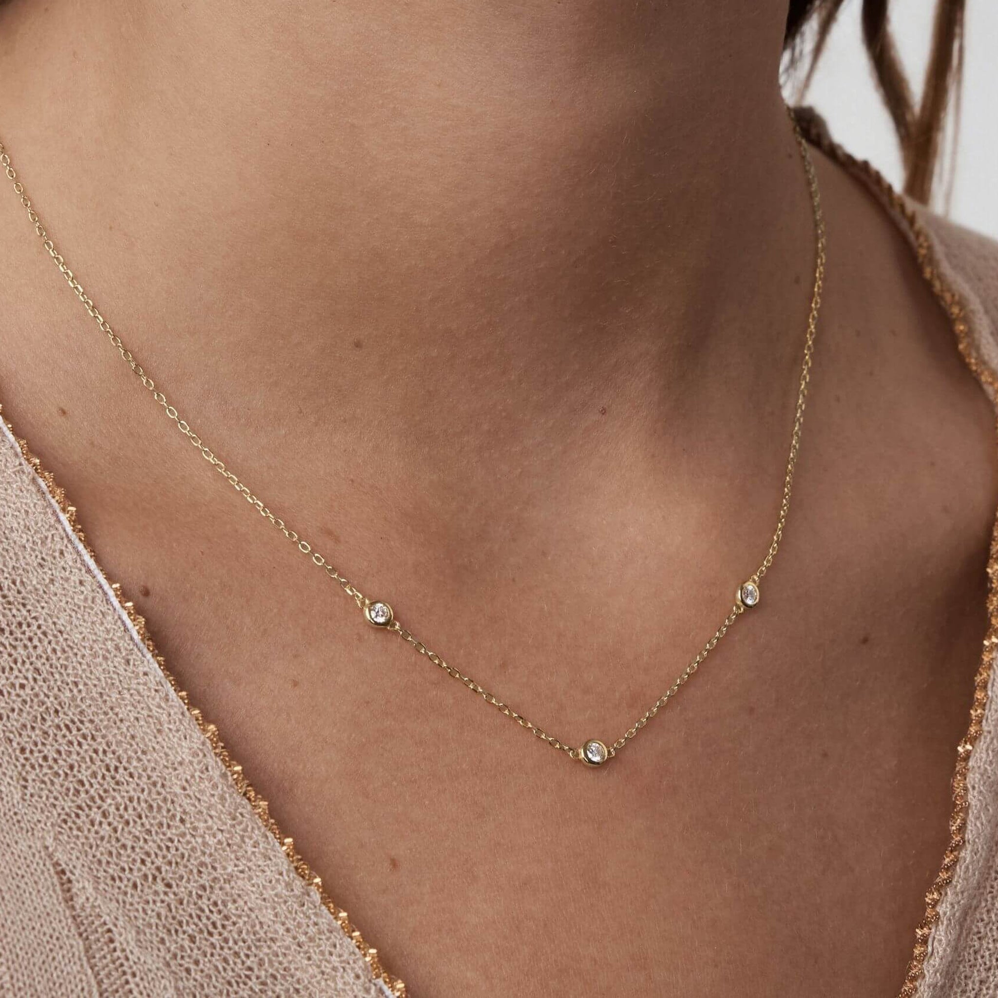 Moissanite satellite necklace worn at the neckline.