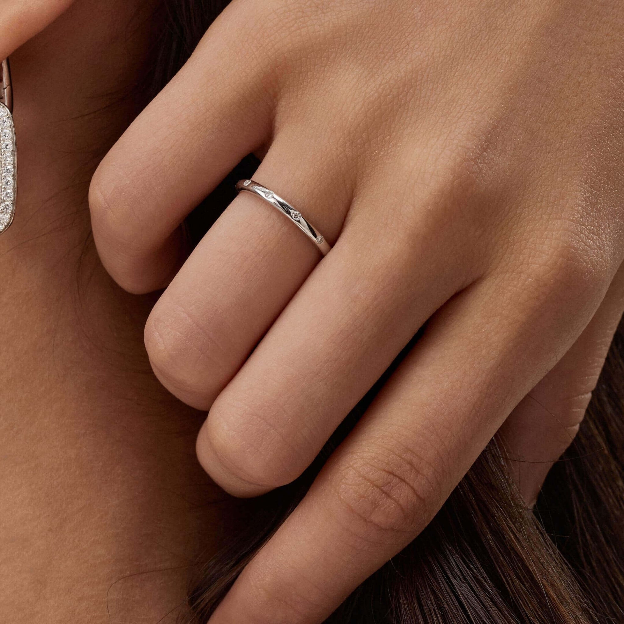 Moissanite station ring worn on a finger.