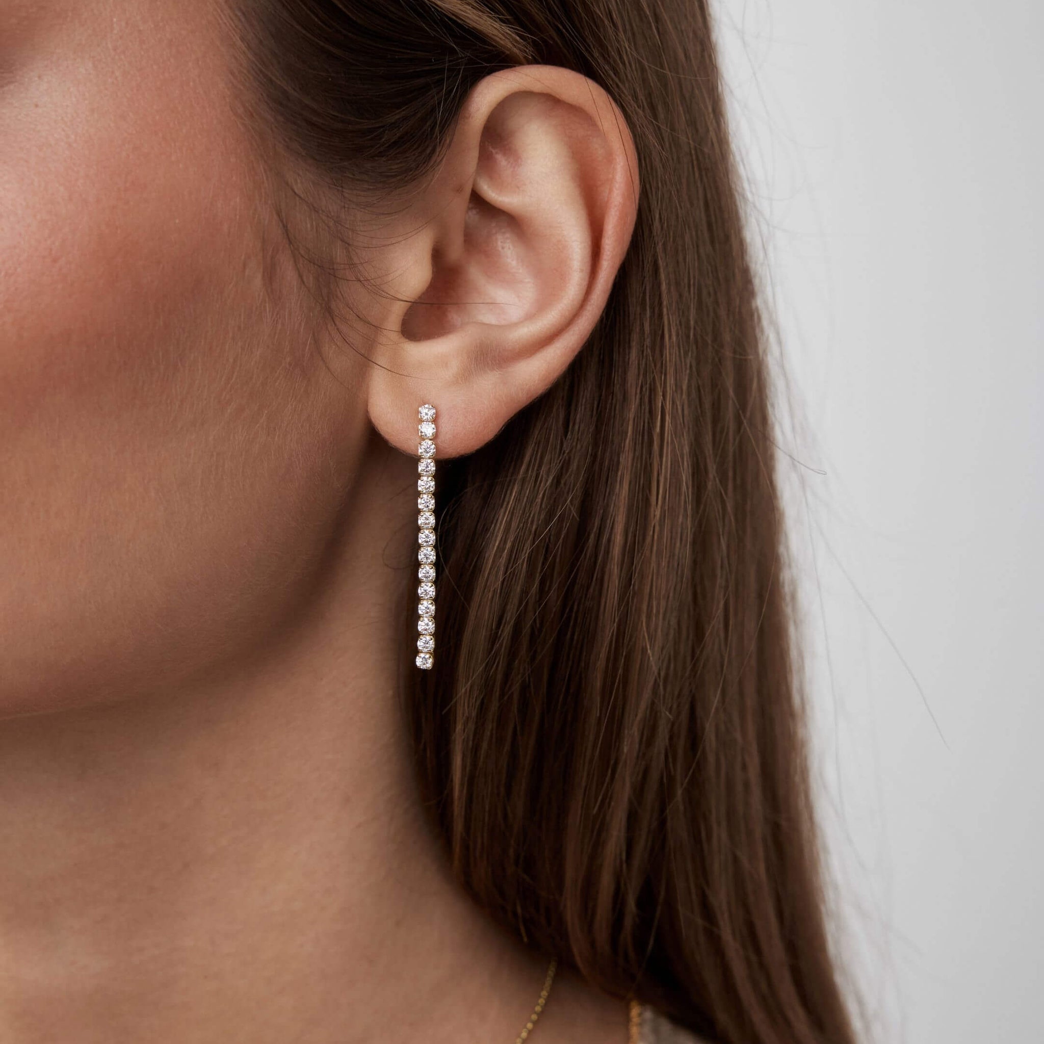 Moissanite tennis drop earrings worn on the ear.