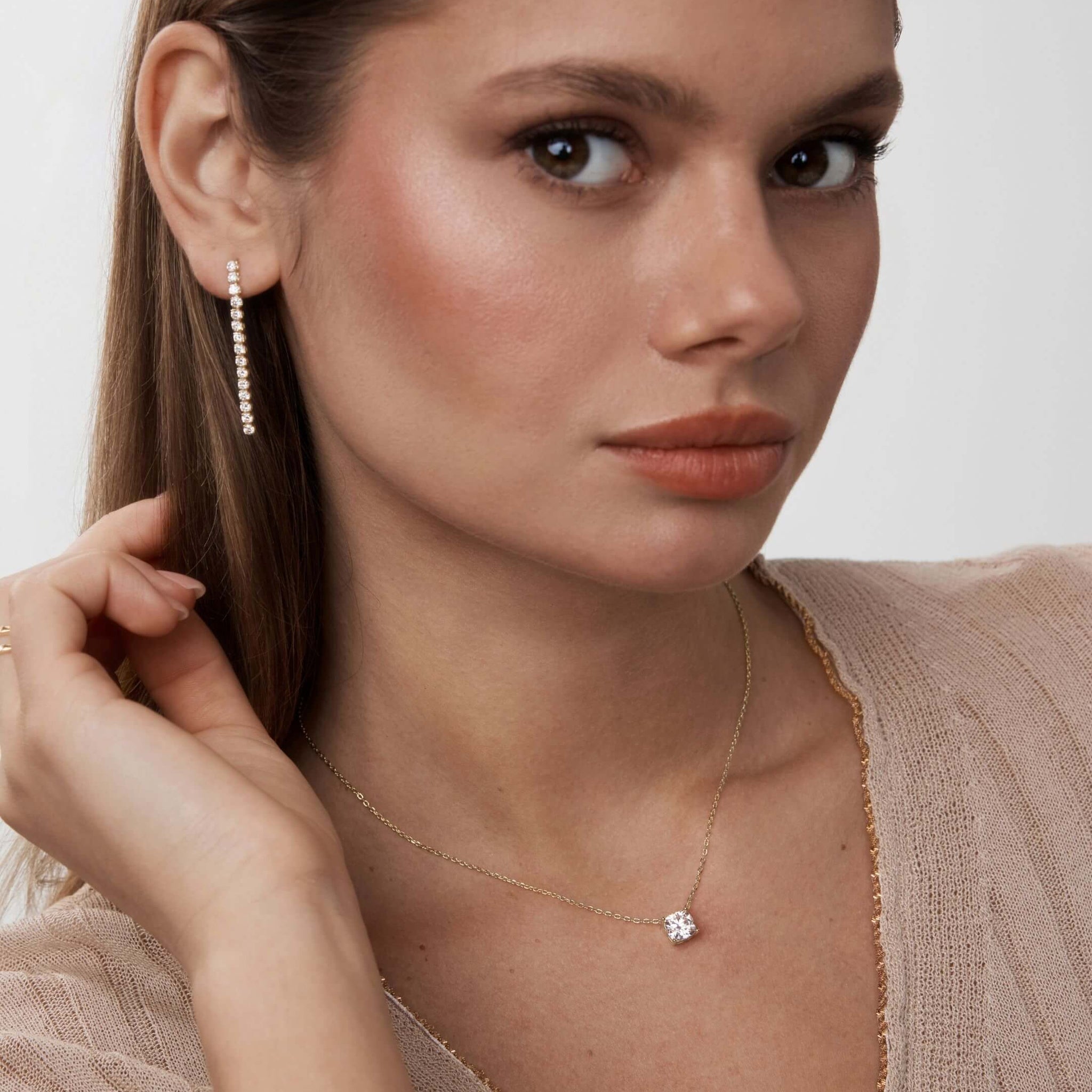Moissanite tennis drop earrings worn on the ear.