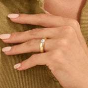 Oval-cut moissanite bezel dome ring worn on a finger.