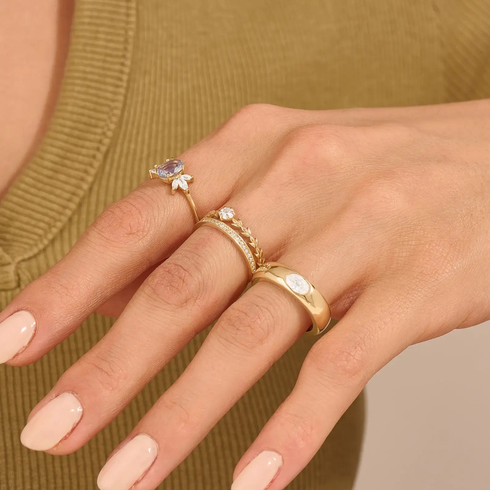 Oval-cut moissanite bezel dome ring worn on a finger.